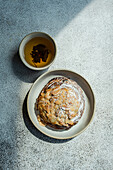 Top view of sweet almond pastry with cup of green tea against gray background in sunlight