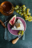 From above assorted yummy snacks with cheese and served on plate placed with grapes and figs and drink