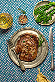 From above delicious sliced roast beef tagliatta served on plate near bowl with broccoli and herbs placed on patterned table towel