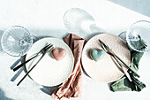 Top view of ceramic plate with cutlery and napkin with heart shaped decor crystal placed on concrete surface at kitchen table for meal during Valentine's day celebration