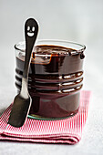 Hot chocolate served in transparent glass with spoon on napkin against blurred background