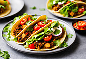 From above of appetizing tacos with lettuce leaves and meat with tomatoes and sour cream served on plate. Generative AI