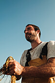 Fro unten Porträt von glücklichen männlichen Seemann in Schürze mit Angeln bewundern atemberaubende Meereslandschaft in Sonnenuntergang auf Segelboot in Soller auf den Balearen in Mallorca
