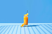 Gepresster Orangensaft garniert mit Orangenscheibe auf blauem Hintergrund