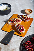 From above appetizing ricotta toast with roasted grapes and lemon zest served with tarragon and pine nuts placed on crusty bread on wooden board on gray table