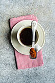 Draufsicht auf eine Tasse würzigen Espresso mit Löffel und roter Paprika auf einer Serviette auf einem grauen Tisch