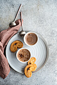 From above cup of coffee with milk and cookies on the tray plate served on the concrete table