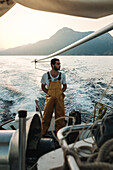 Gesamtansicht eines nachdenklichen männlichen Fischers in Uniform, der die Meereslandschaft beim Fischen in Soller nahe der Baleareninsel Mallorca bewundert