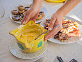 From above of anonymous cook presenting appetizing yellow sauce fresh hotdog and mushrooms on table with plates