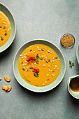 Top view of appetizing vegetarian pumpkin cream soup with herbs and sesame seeds served in bowls on table