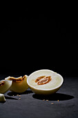 Side view of a fresh melon cut in half on black background