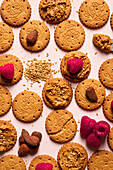 Top view of appetizing crispy biscuits with peanut butter with sesame seeds raspberries and nuts served on table as abstract background