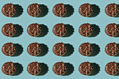 Top view of many donuts without hole covered with chocolate and nuts on blue background