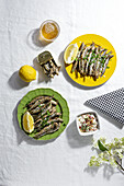 From above of delicious fried anchovies served on plates with lemon and placed on white table with glass of beer