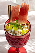 From above yummy yogurt with grapes and watermelon garnished with cinnamon stick and mint and served on table in summer