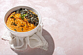 From above of appetizing healthy pumpkin puree with seeds and seasoning served in white ceramic bowl on table in daylight