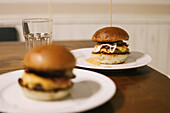 Scrumptious hamburger with toothpick while serving on white plate placed on table