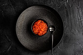 From above red fresh trout fish caviar served in a bowl on concrete table background