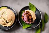 Top view of sweet ice cream scoops decorated with pecan nuts and mint leaves on plates