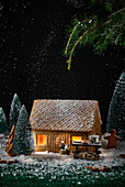 Ein kleines Häuschen aus Keksen wird mit Weihnachtsdekoration geschmückt