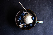 From above bowl full of delicious ripe blueberries placed on black background