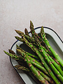 Top view of bunch of fresh green asparagus placed in bowl on table