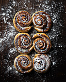 Appetizing baked sweet cinnamon rolls with white cream topping served on table in bakery