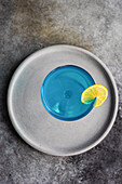 Glass of blue kamikaze drink on stone table in modern style