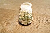 Row of similar metal crypto coins with letter on desk on shiny blurred background