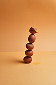 Ein Stapel frischer brauner Eier balanciert auf einem Tisch mit pfirsichfarbenem Hintergrund im Atelier