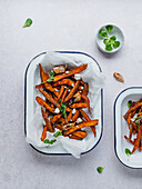 High angle of delicious sweet potato fries with sour cream and herbs served on table