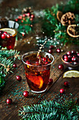 Top view of glasses with cranberries with lemon next to Christmas decoration