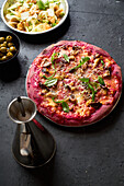 Purple colored rustic pizza with beetroot and vegetarian topping. Top view healthy food recipe