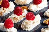 Appetizing delicious creamy dessert with fresh ripe raspberries with pecan nuts placed on plate in cafe