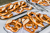From above of delicious baked knot shaped pretzels served on metal trays and placed on table during outdoor event