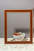 High angle of white bowl with tasty poke dish and chopsticks placed behind frame on table covered with sesame seeds