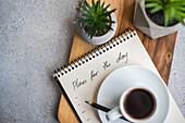 Plans for the day and morning cup of coffee on the table with green plants in the pot