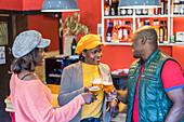 Group of African American happy friends clinking glasses with beer while enjoying weekend together in bar