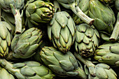 Top view full frame of bunch of fresh green artichokes placed on stall in local market