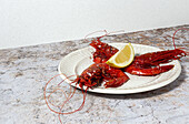 Tasty seafood of cooked red shrimps with fresh lemon slices and coarse salt on white background