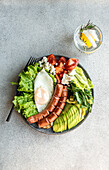 healthy ketogenic lunch plate with vegetables, fried egg and sausages served on the concrete plate