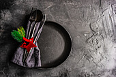 From above ceramic plate setting for Christmas dinner on concrete table on dark background