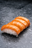 Set von ähnlichen schmackhaften traditionellen japanischen Sushi mit weißem Reis und frischem Lachs auf Marmortisch in hellem Raum serviert