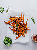 High angle of delicious sweet potato fries with sour cream and herbs served on table