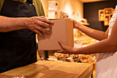 Unrecognizable woman taking carton box with goods from male vendor while visiting shop