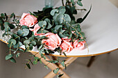 Von oben gesehen rosa Rosenstrauß mit grünen Blättern auf dem Tisch liegend