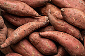 Draufsicht Vollbild von roten rohen Süßkartoffeln zusammen als Hintergrund platziert