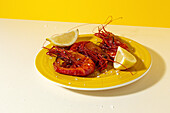 Tasty seafood of cooked red shrimps with fresh lemon slices and coarse salt on two color background