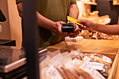 Cropped unrecognizable woman using credit card to pay for goods to vendor in zero waste grocery store