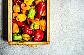 From above wooden box with organic bell peppers on the concrete background